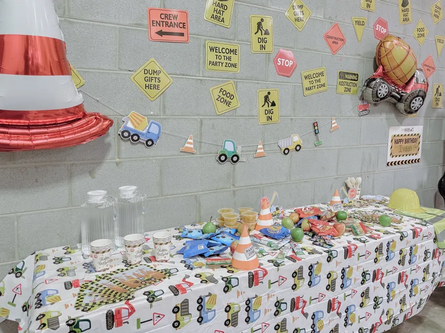 A construction-themed birthday party table with traffic cones, road signs and themed decorations.