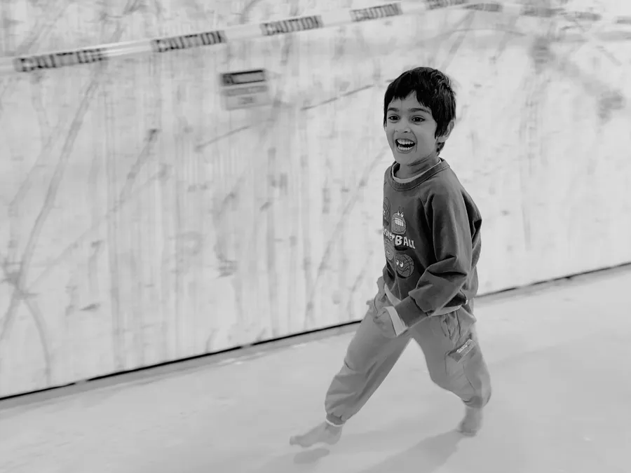 Black and white photo of a birthday boy running and laughing.