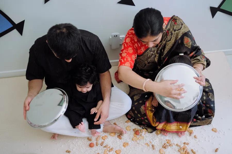 Seen from above, parents shower their baby with rice, berries and nuts during the Makar Sankranti Bornhan berry shower.