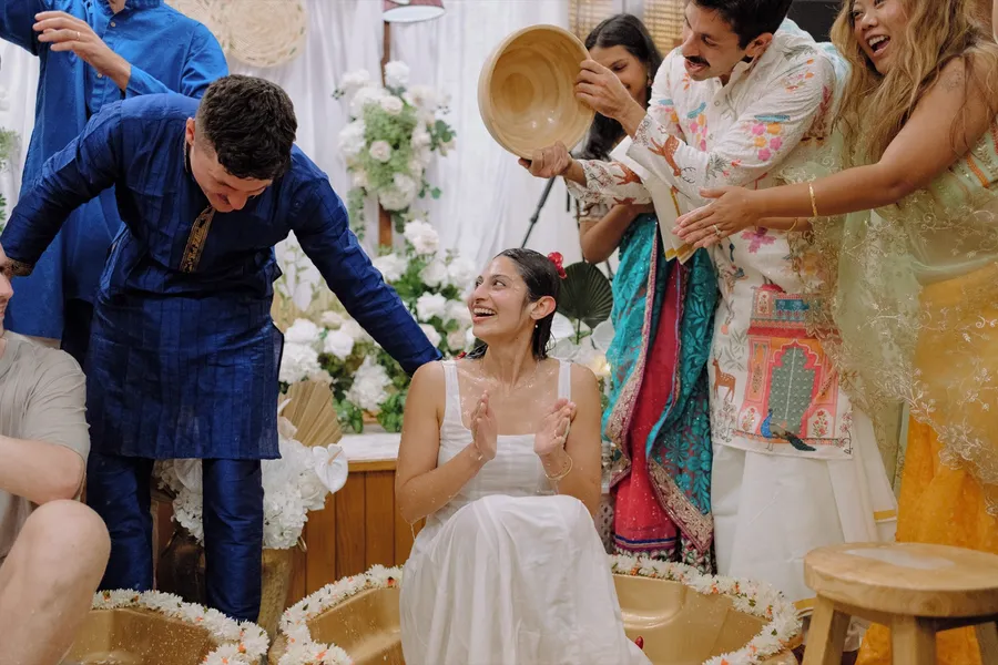 Family and friends laugh as they pour bowls of coconut milk over the seated bride during the playful part of the Roce.