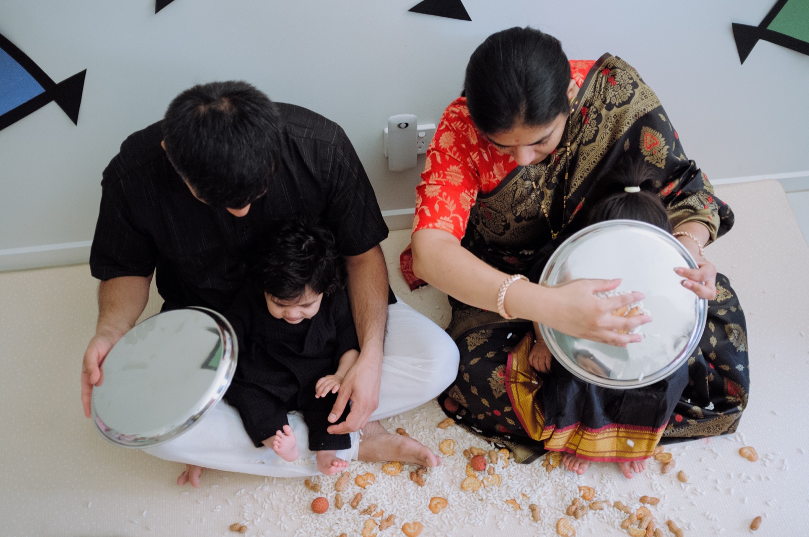 Seen from above, parents shower their baby with rice, berries and nuts during the Makar Sankranti Bornhan berry shower.